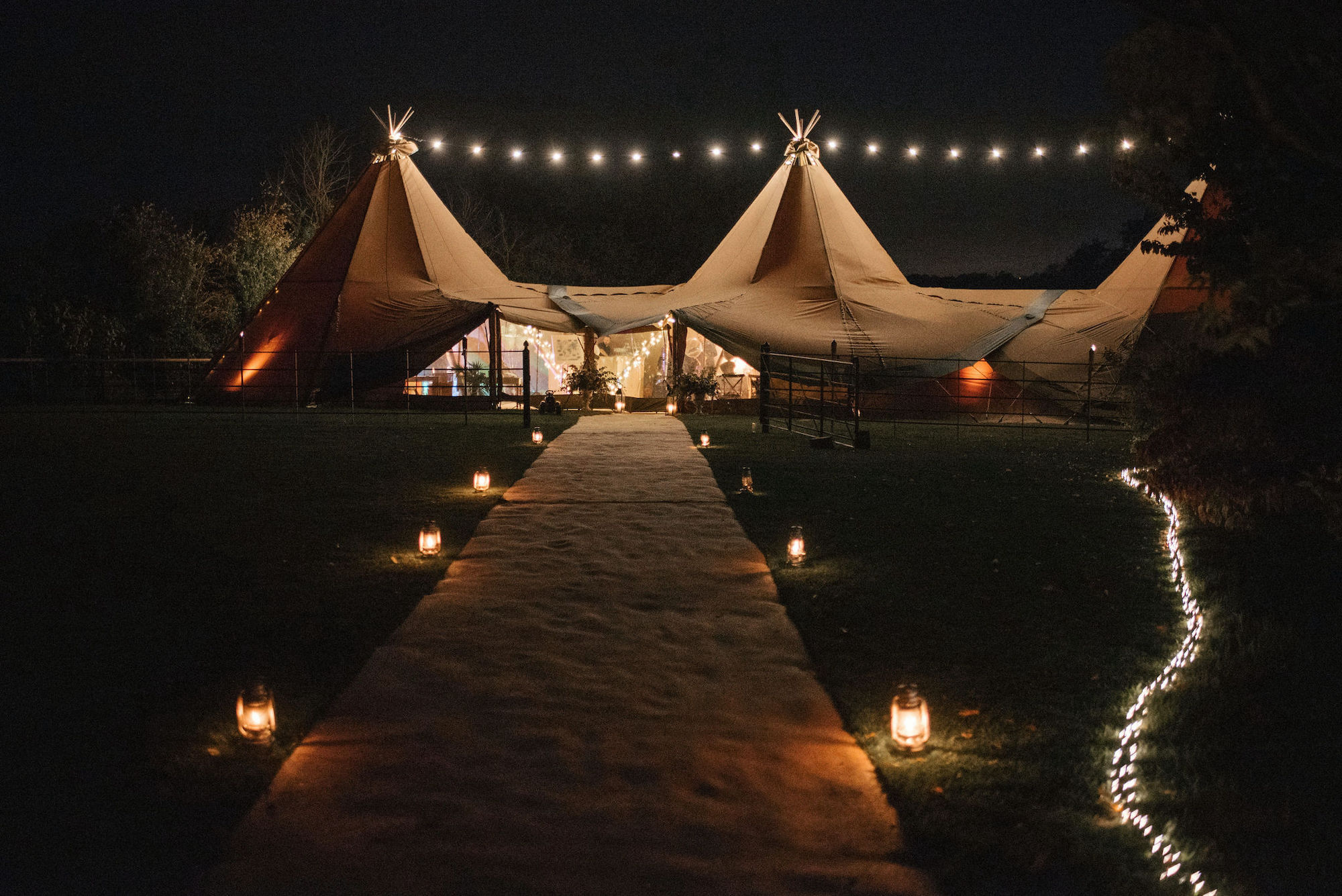 Wedding tipis entrance with lit pathway at night