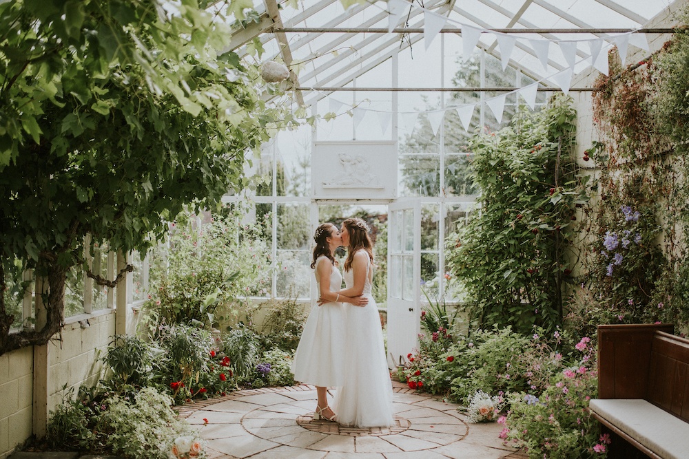 Brides embracing in side glass house at wedding venue