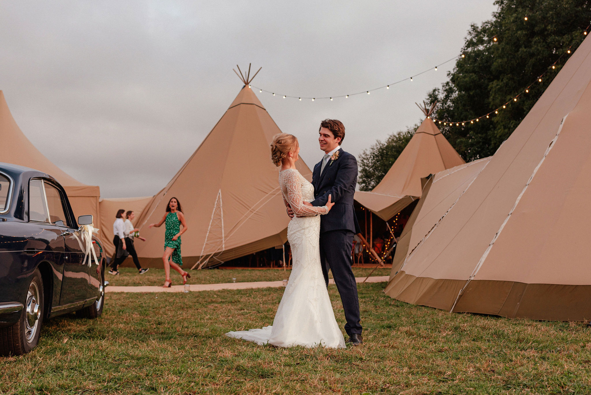 Bride and groom embracing in front of wedding tipis